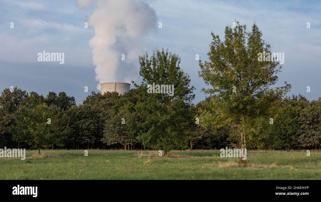 Nuclear power station in the distance with steam coming out of the cooling tower against the sky Stock Photo