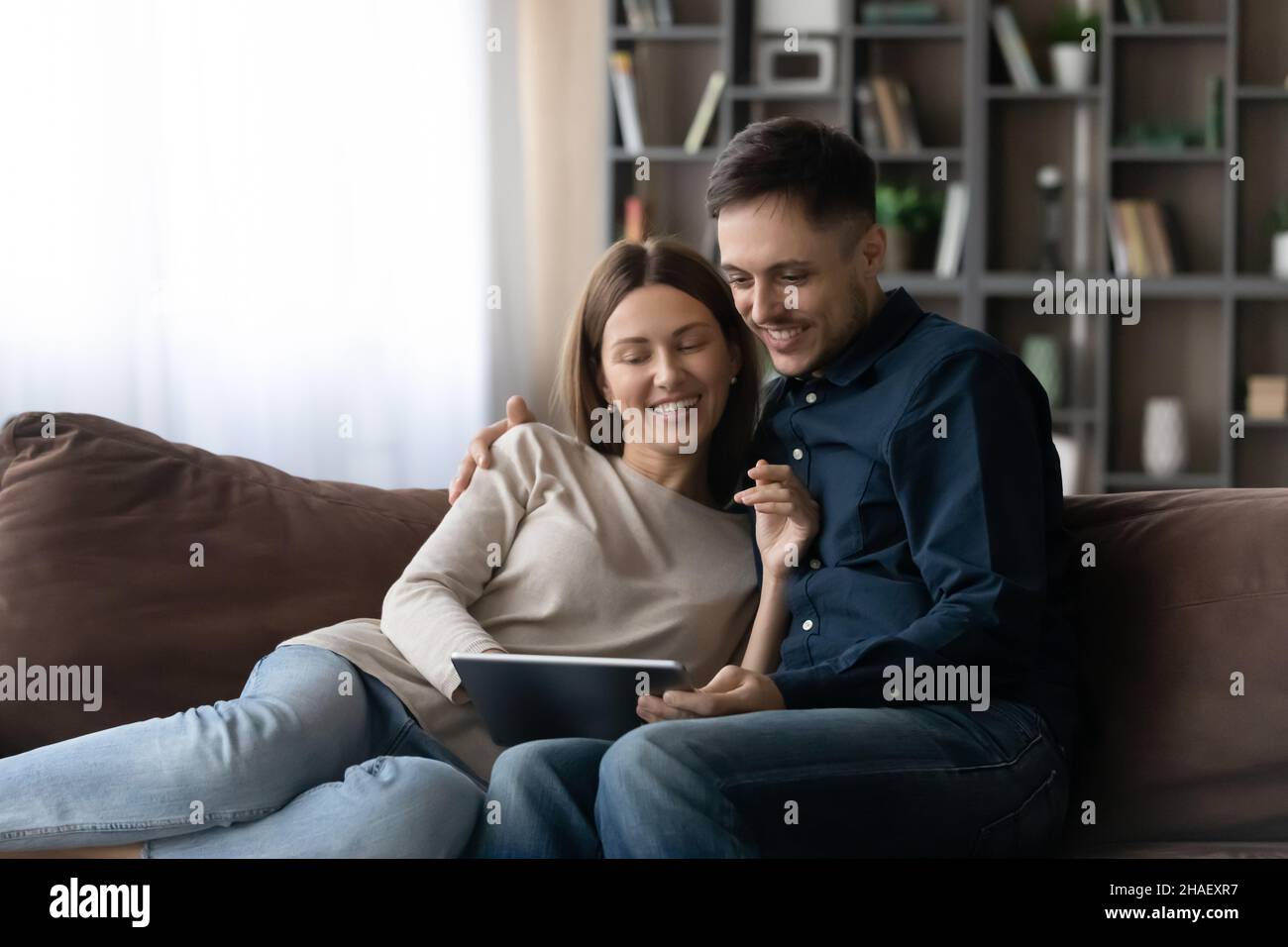 Happy relaxed young family couple using digital computer tablet. Stock Photo