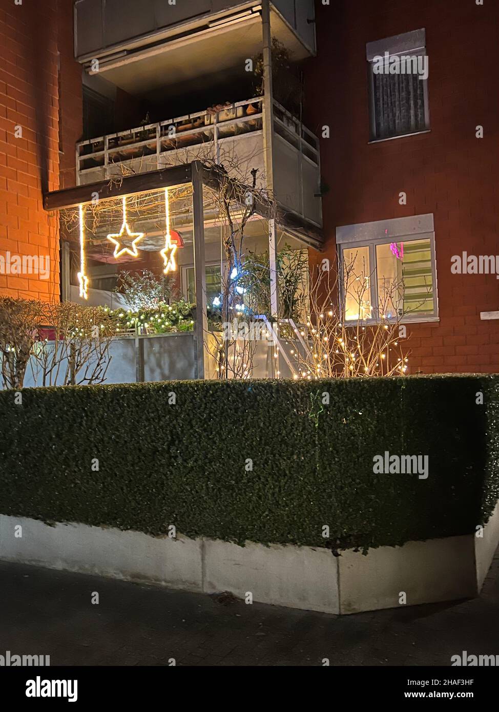 Christmas lights and stars on balcony of a residential building in a village in Switzerland. Colorful lights glitter on December evening. Stock Photo