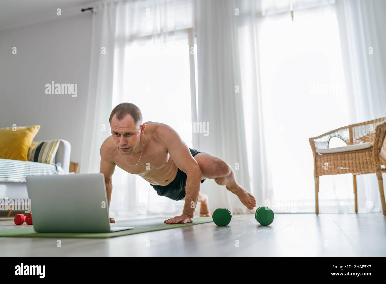Home workout in the living room. Young muscular body man making ...