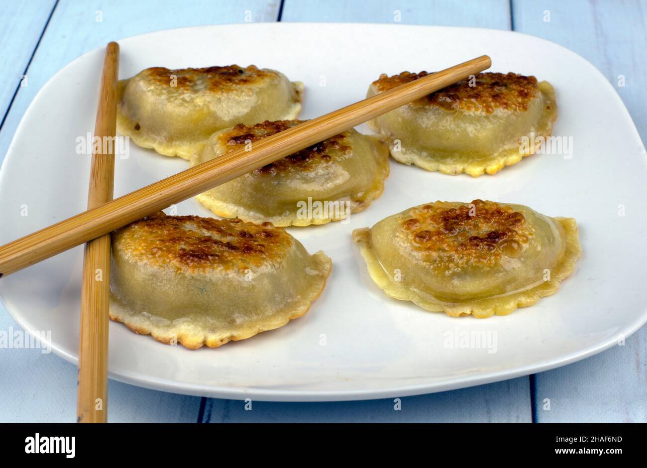 beef dumplings just out of the pan and arranged on a platewith chopsticks on top Stock Photo