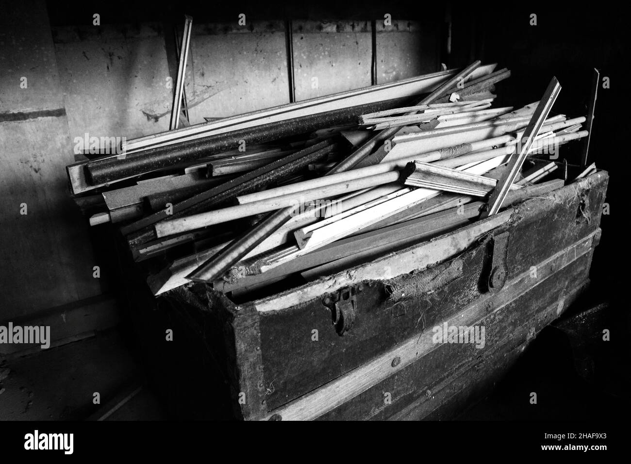 black and white photo of an old chest filled with picture framing wood Stock Photo