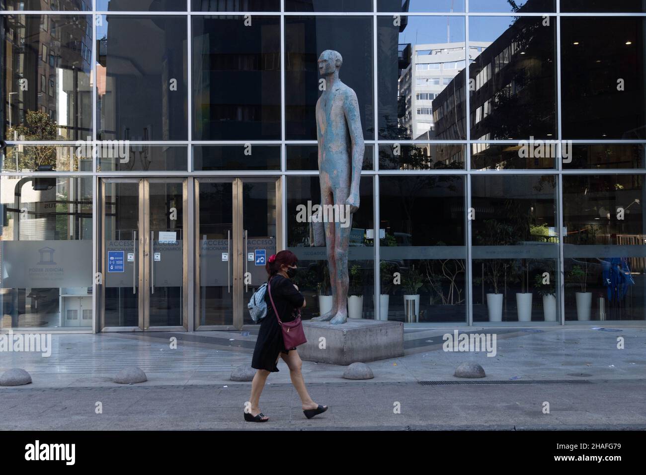 Santiago, Metropolitana, Chile. 12th Dec, 2021. A woman with a face mask walks in front of a statue in downtown Santiago, Chile. (Credit Image: © Matias Basualdo/ZUMA Press Wire) Stock Photo