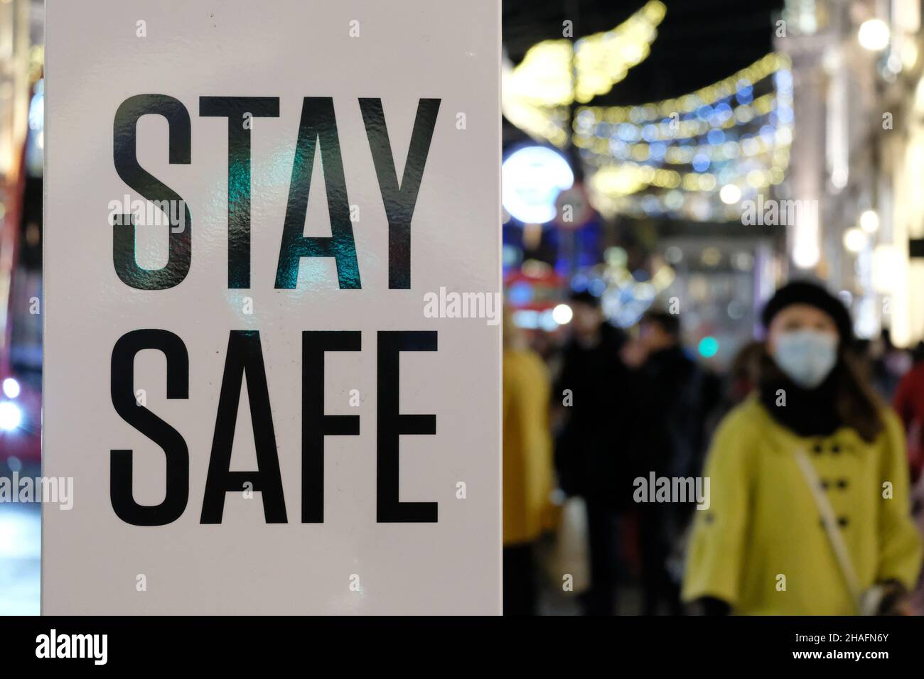 London, UK, 12th Dec, 2021. A hand sanitiser stand printed with the words 'stay safe'. Crowds of shoppers and those enjoying the Christmas lights fill Regent Street as the UK Covid alert level is raised to four, amid a further rise of Omicron variant cases.  Credit: Eleventh Hour Photography/Alamy Live News Stock Photo