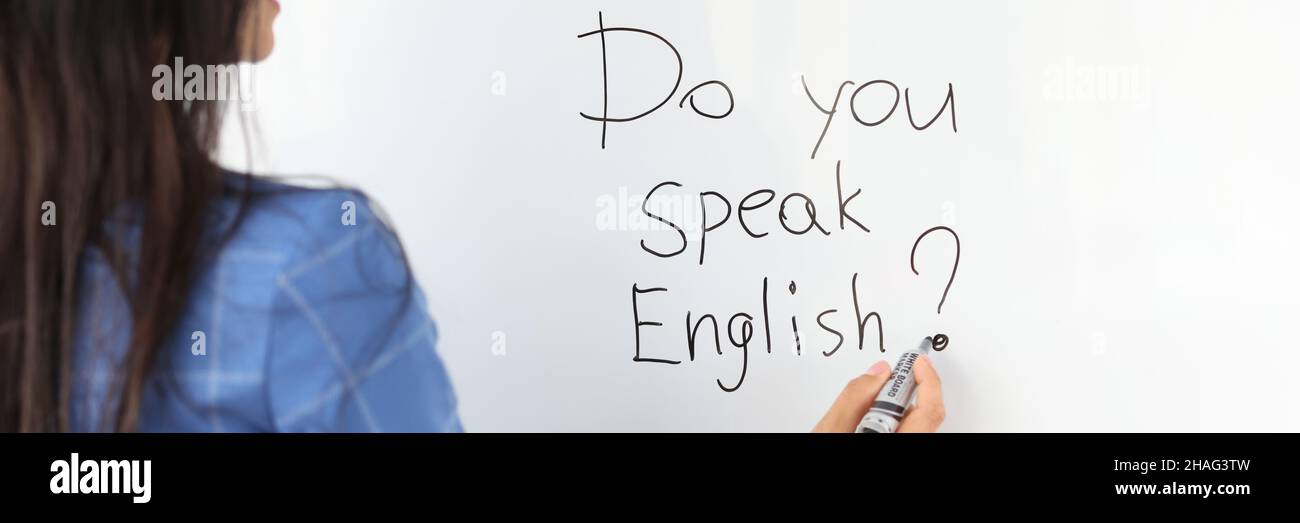 Woman teacher writes with marker do you speak english on white board Stock Photo
