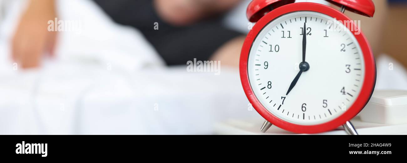 Rested man reaches for watch button to turn off daily alarm and wake up