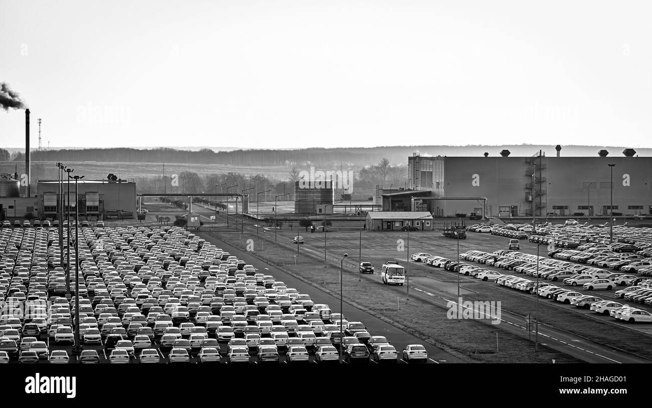 Volkswagen Group Rus, Russia, Kaluga - NOVEMBER 17, 2020: Rows of a new cars parked in a distribution center and a car factory buildings. Parking in t Stock Photo