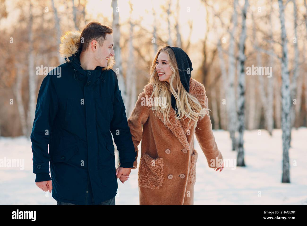 Loving young couple walking playing and having fun in winter forest park. Stock Photo