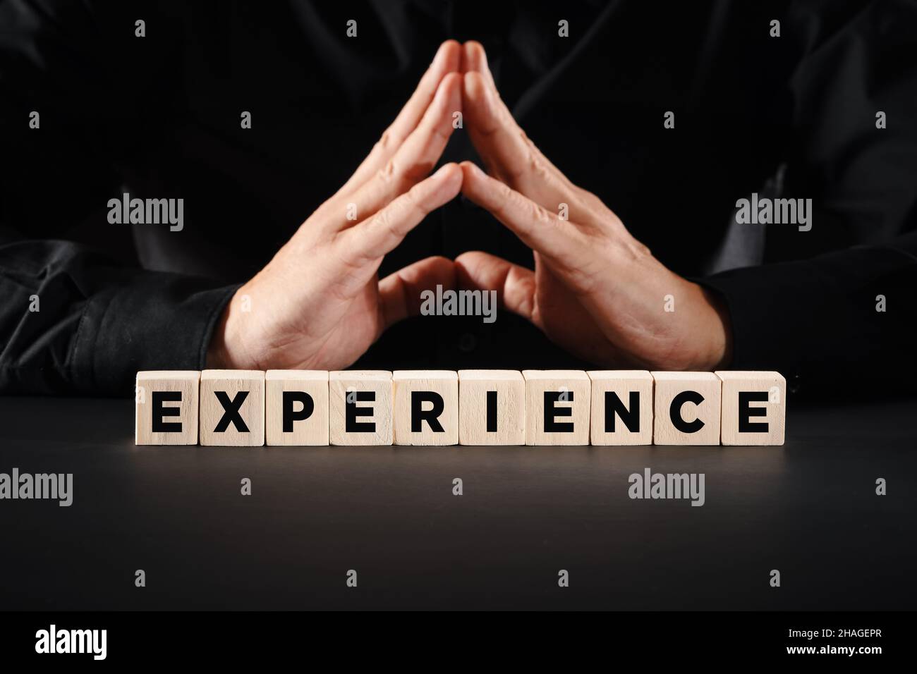 Man with clasped hands with the word experience on wooden blocks. Work experience in business or education concept. Stock Photo