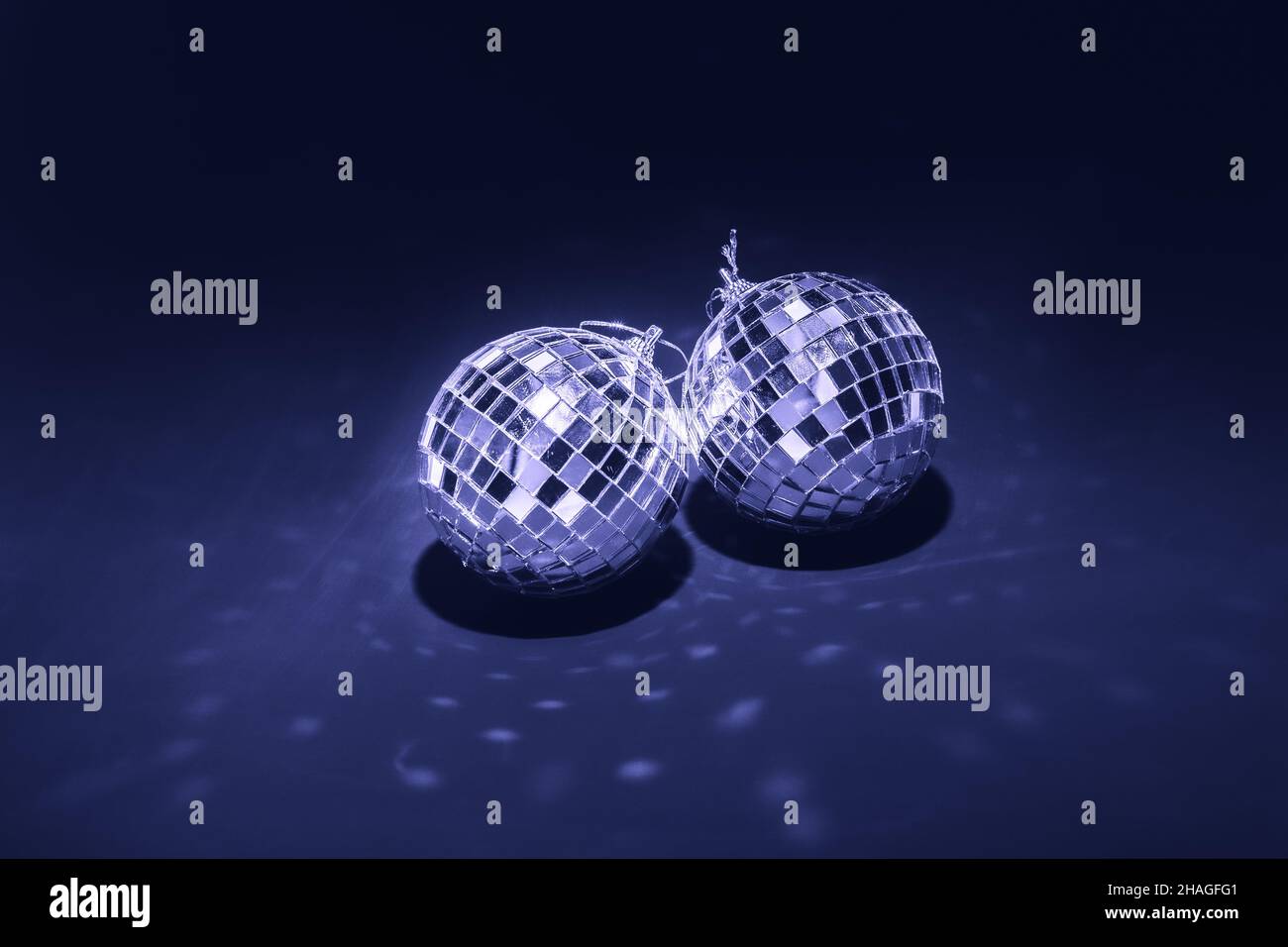 two mirror balls illuminated by bright light on dark violet background Stock Photo
