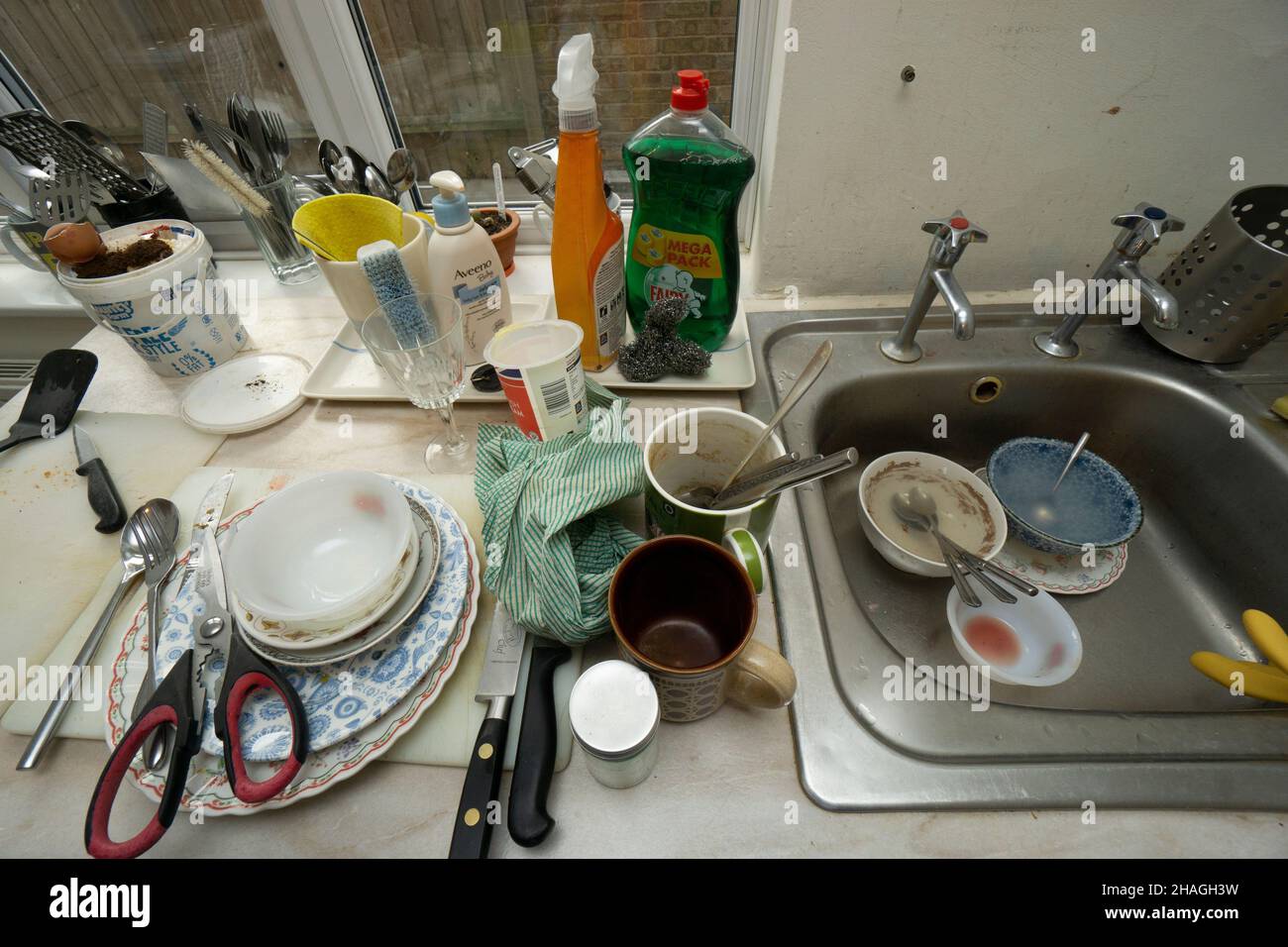 kitchen worktop and sink with washing up of dirty plates cups knives