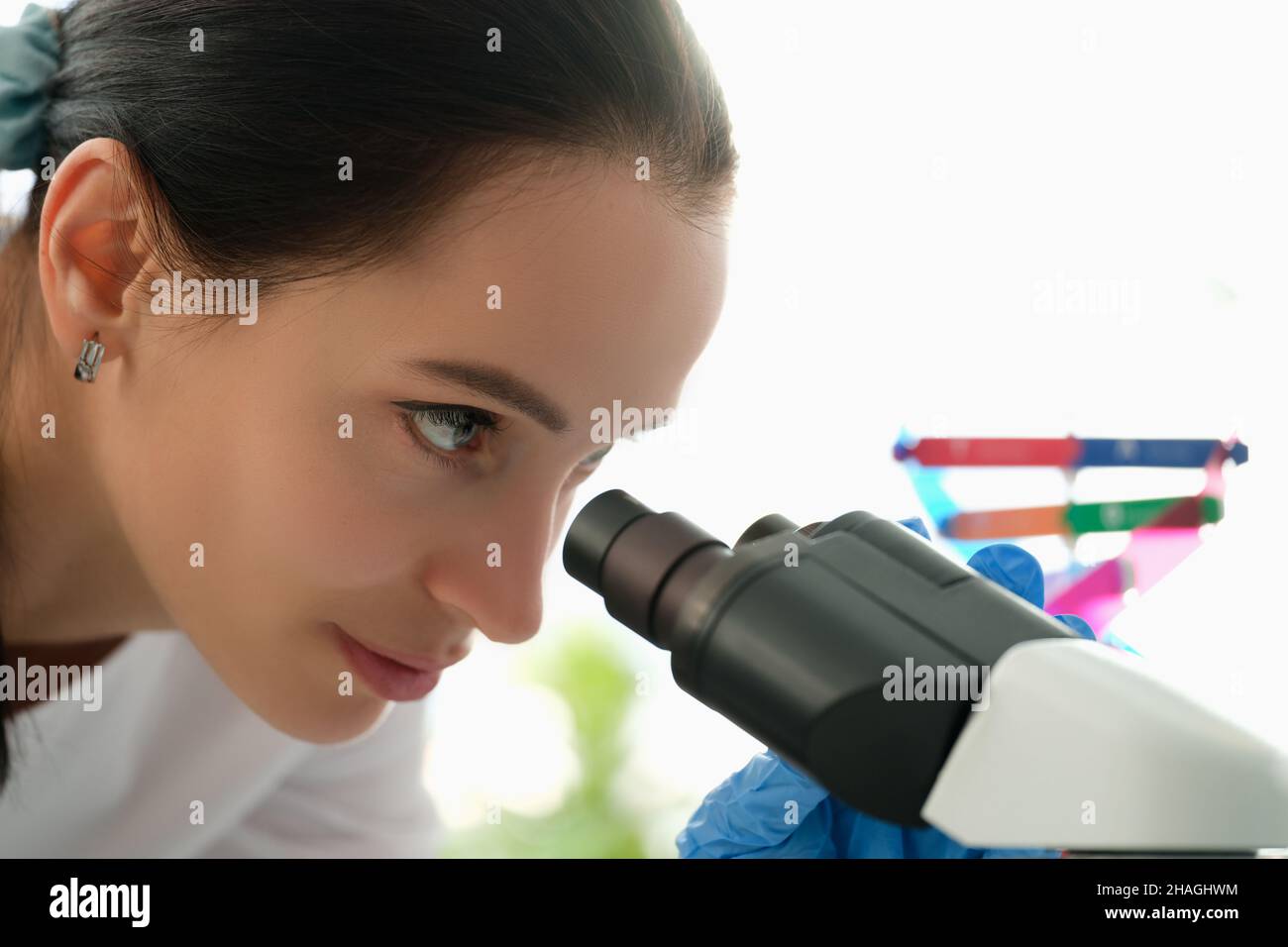 Beautiful woman looks through a microscope, profile view Stock Photo