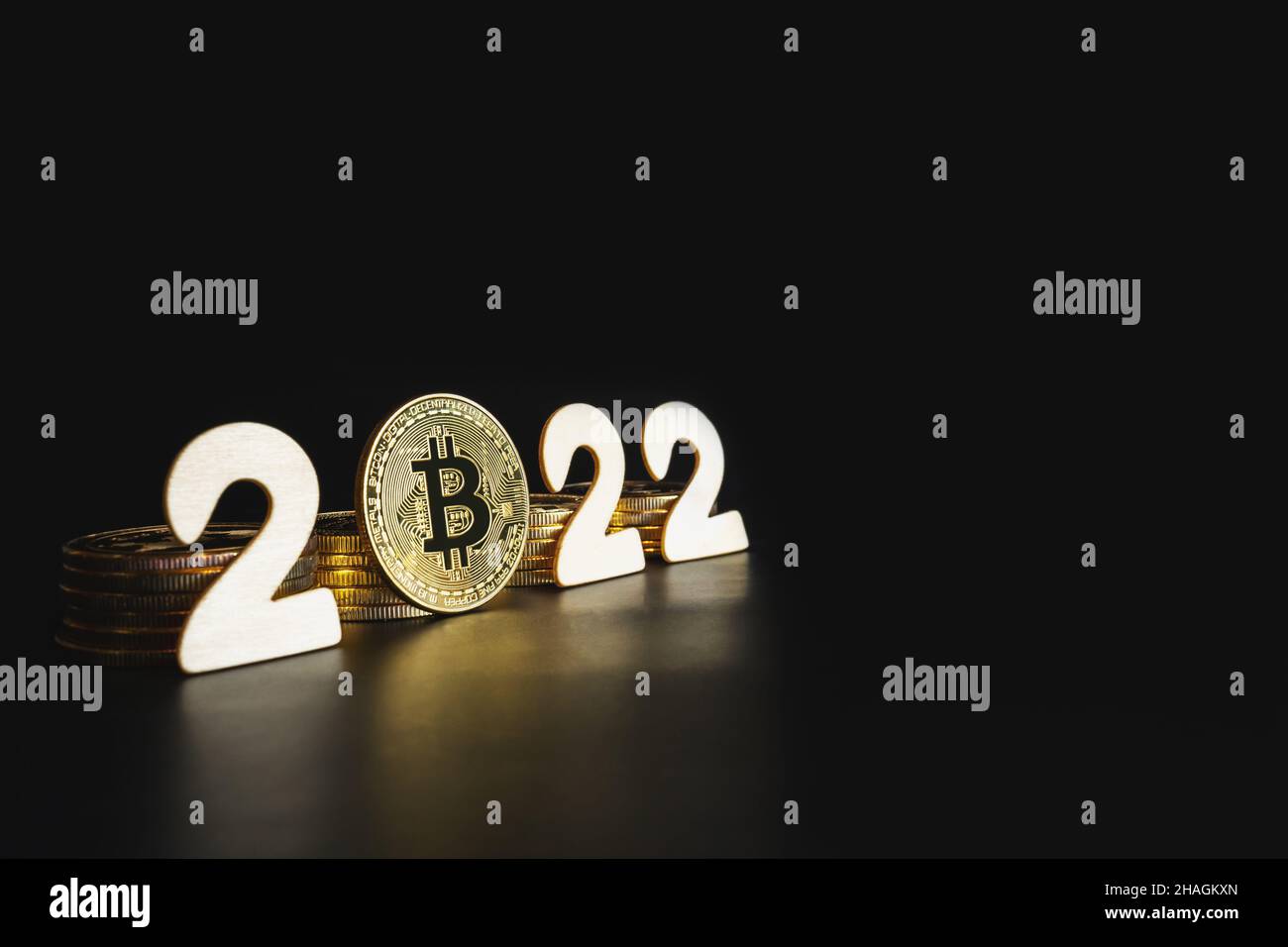 Bitcoin 2022. Single Bitcoin gold coin next to numbers on black background with copy space. Price, future value of BTC crypto prediction concept. Stock Photo