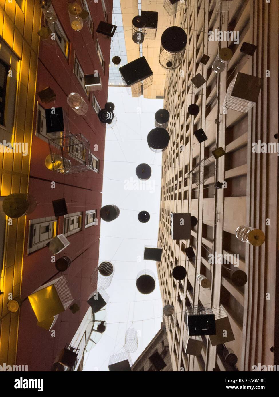 Forgotten Songs is an artistic installation of empty birdcages hanging in the sky on the angle of Place lane way, Sydney NSW Australia Stock Photo