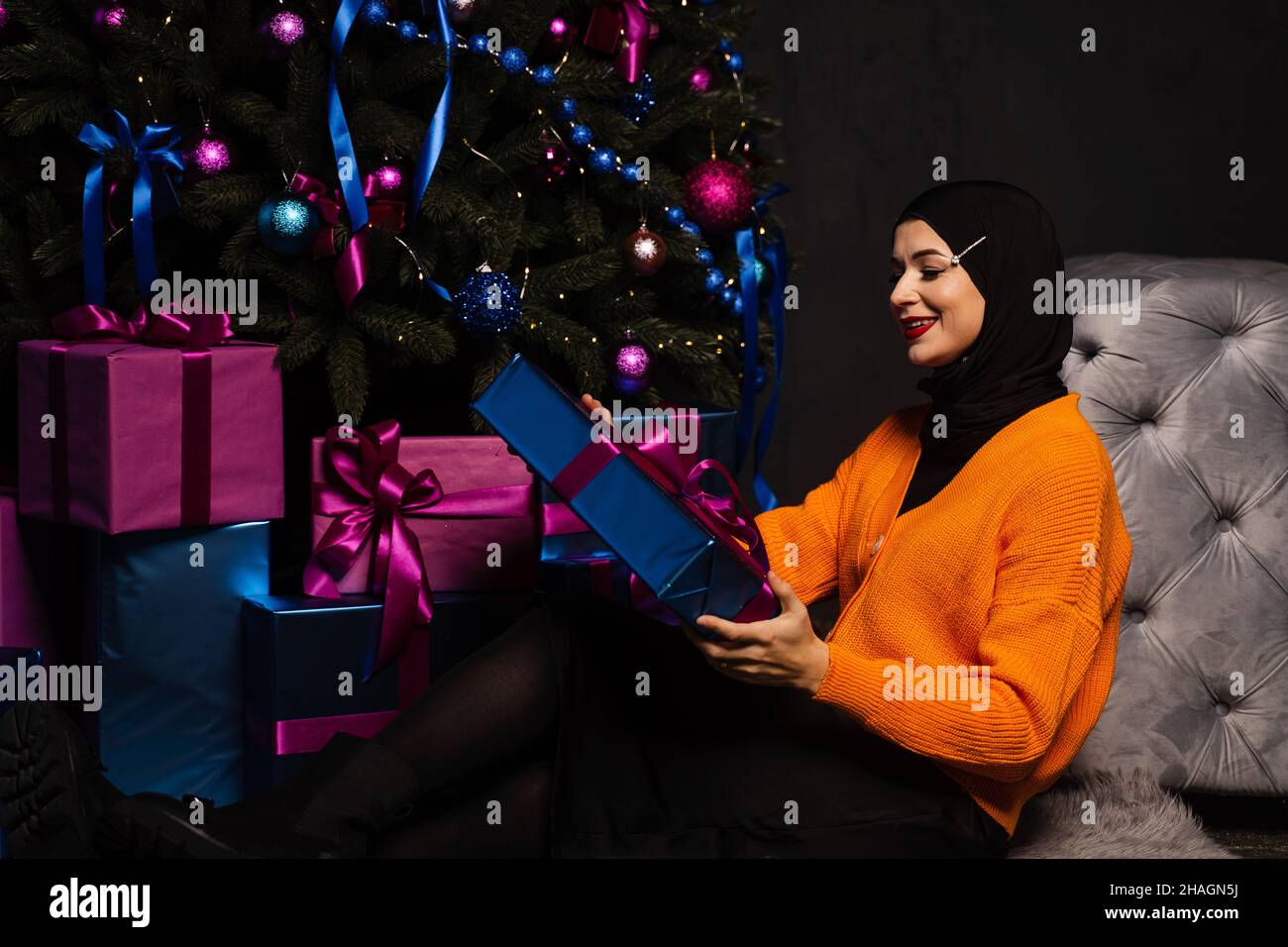 Muslim woman with gift near new year tree. Christmas celebration of
