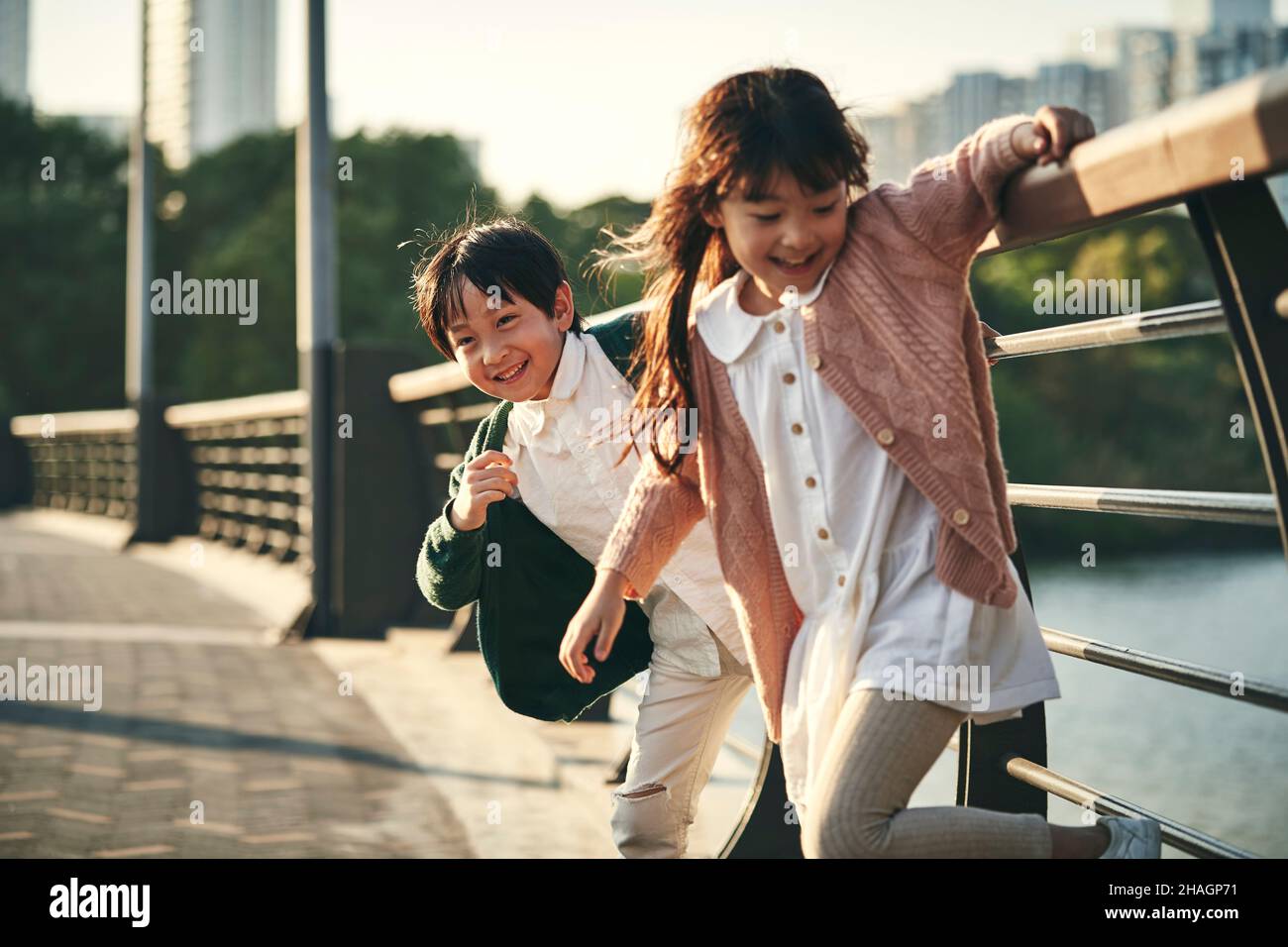 two happy asian children having good time playing in city park Stock Photo