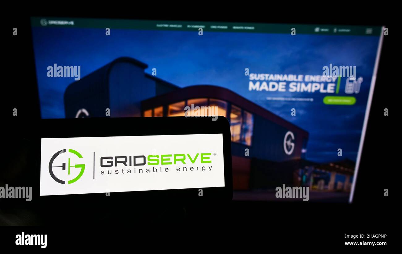 Person holding smartphone with logo of British company GRIDSERVE Sustainable Energy Limited on screen in front of website. Focus on phone display. Stock Photo