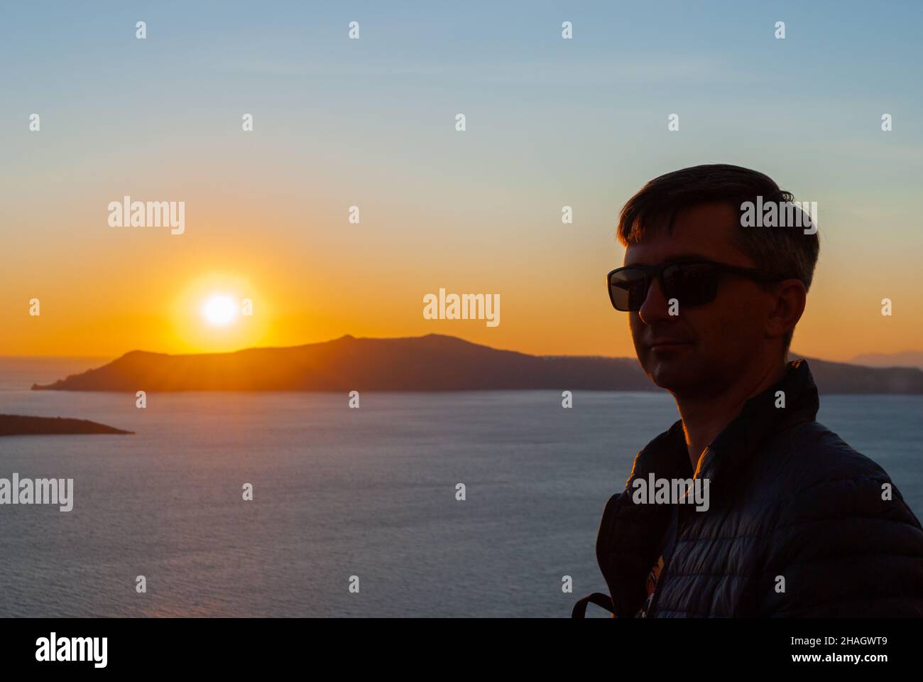 Silhouette of a man's head and shoulders in the background of a sunset in Santorini, Greece Stock Photo