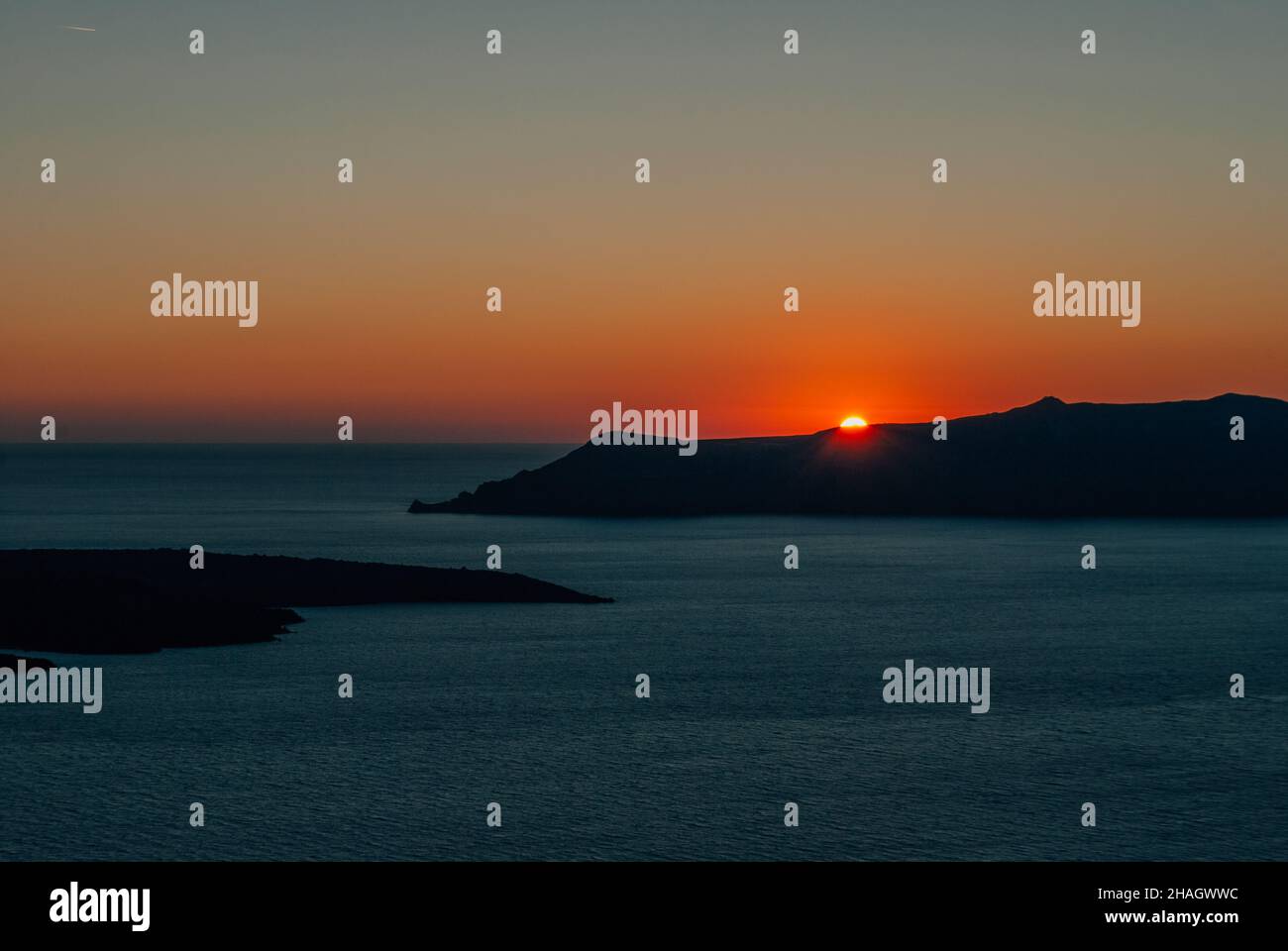 The sun at sunset almost disappeared behind the island, Santorini, Greece Stock Photo