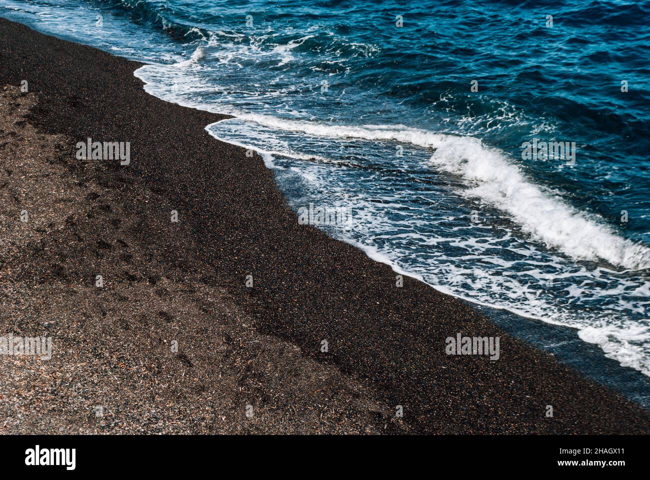 Diagonal line between the sea wave and the black sand of Kamari Beach Stock Photo