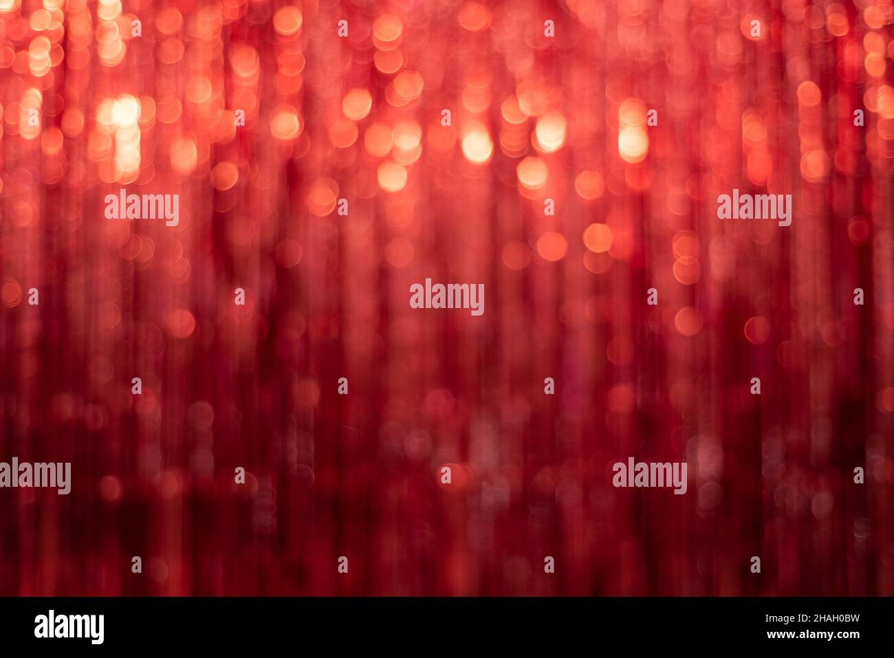 Festive red background with tinsel out of focus and beautiful bokeh Stock Photo