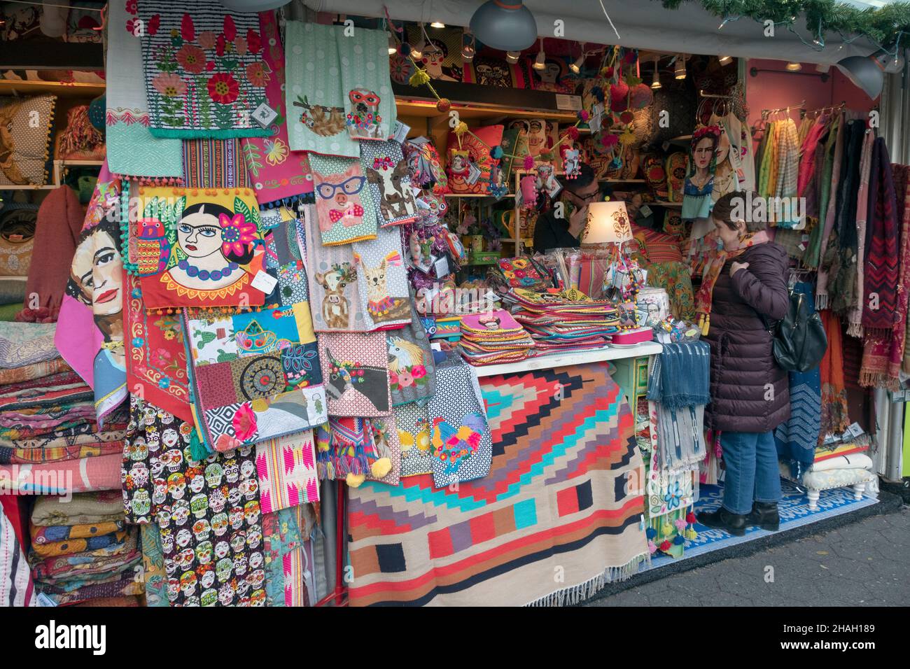 A woman shopper at the Union Square Holiday market browses at a booth that has several Frida Kahlo items. In lower Manhattan, New York City. Stock Photo