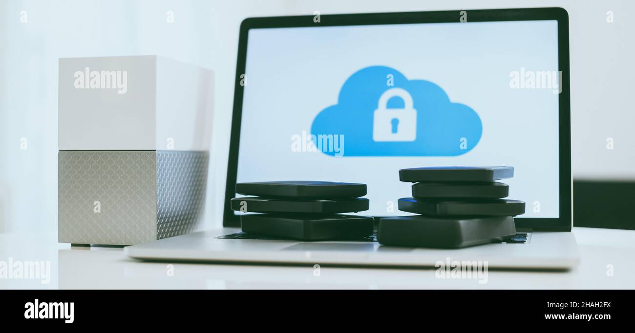 Laptop on the desk with network attached storage. Computer, nas and stack of hard drives on the table. Cloud technology, online disk, remote backup, s Stock Photo