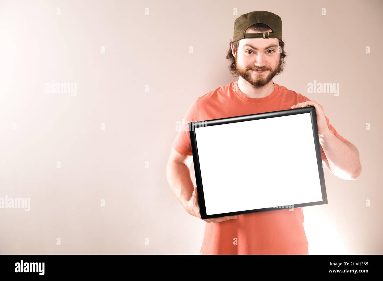 Young handsome bearded man showing blank signboard, isolated on gray background Stock Photo