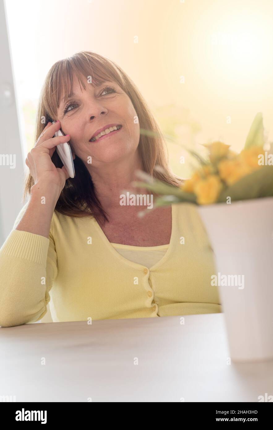 Mature woman talking on mobile phone, light effect Stock Photo - Alamy