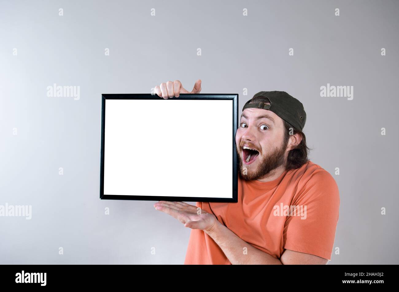 Young handsome bearded man showing blank signboard, isolated on gray background Stock Photo