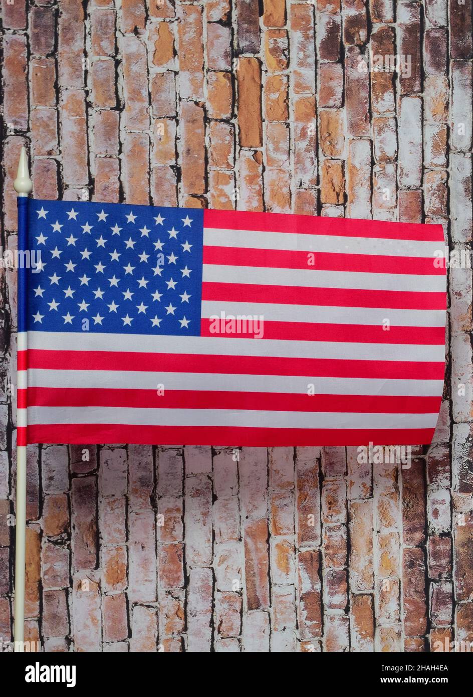 USA flag on white flagpole on old brick wall background Stock Photo - Alamy