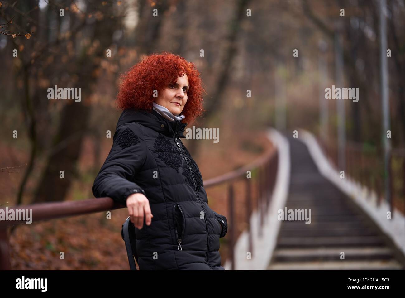 Portrait of a curly haired redhead woman in black winter coat in the ...