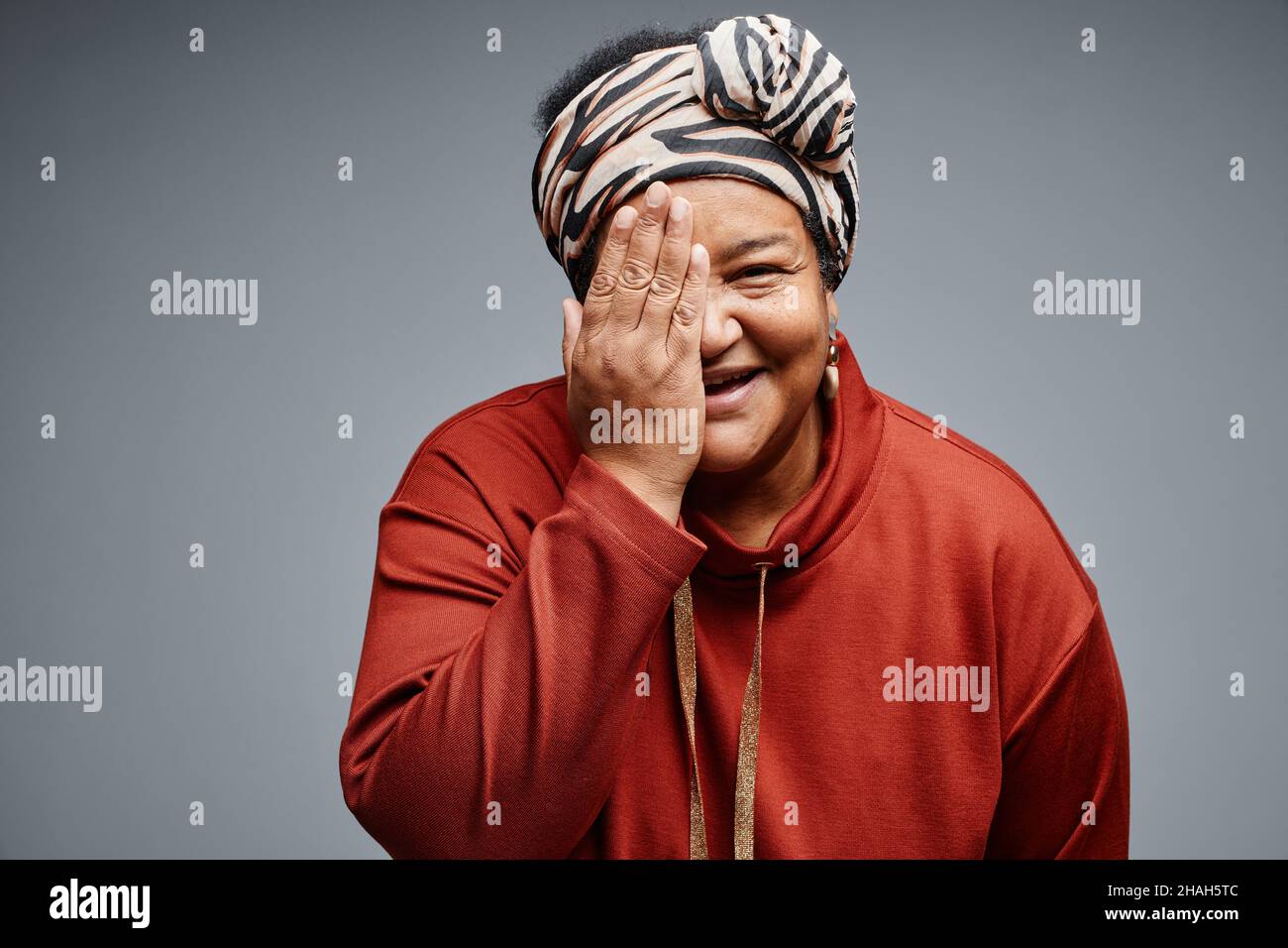 Waist up portrait of carefree black senior woman hiding face against ...