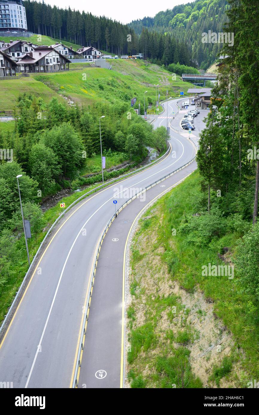 Empty winding asphalt road in a ski resort in summer. View from a high angle. In the background there are beautiful holiday houses Stock Photo