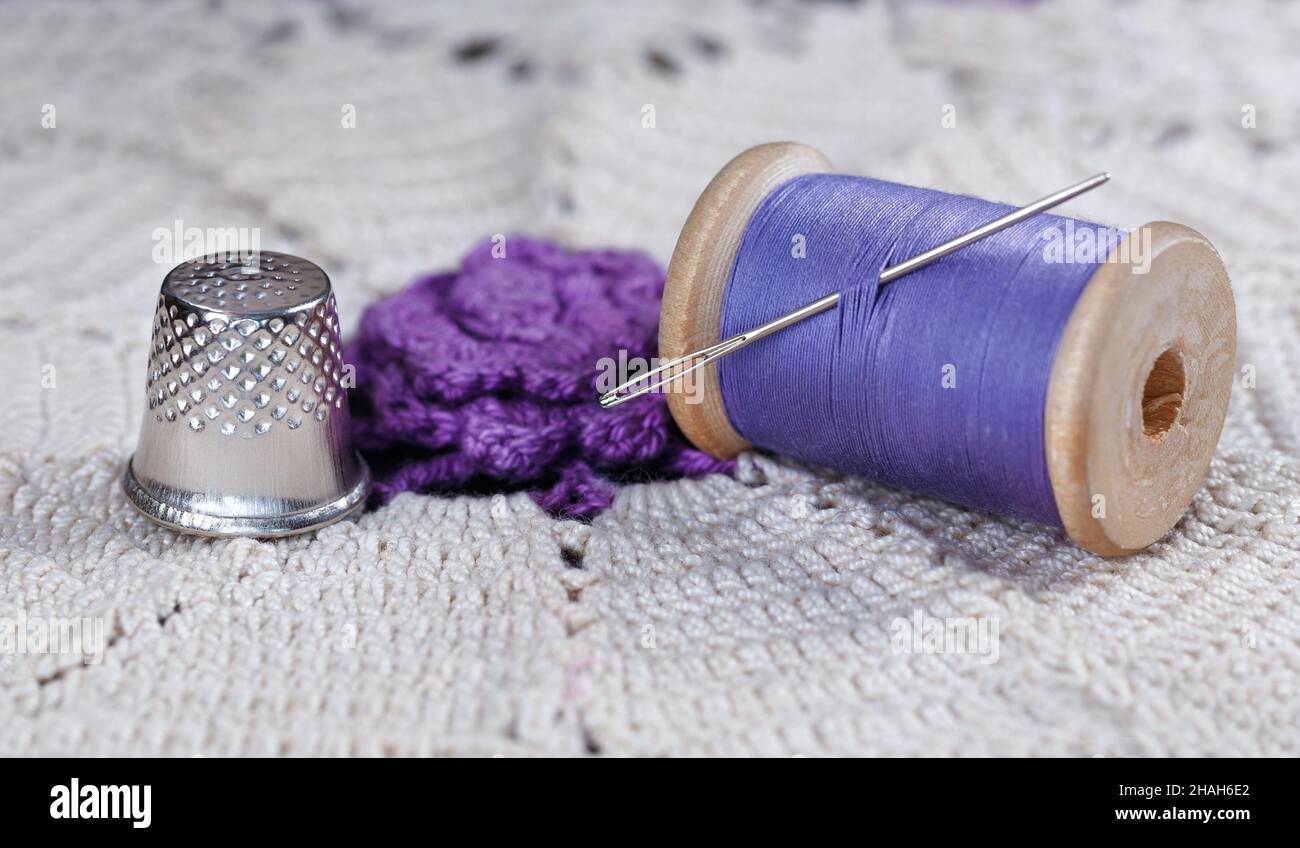Wooden spool with thread, thimble and needle on lace Stock Photo