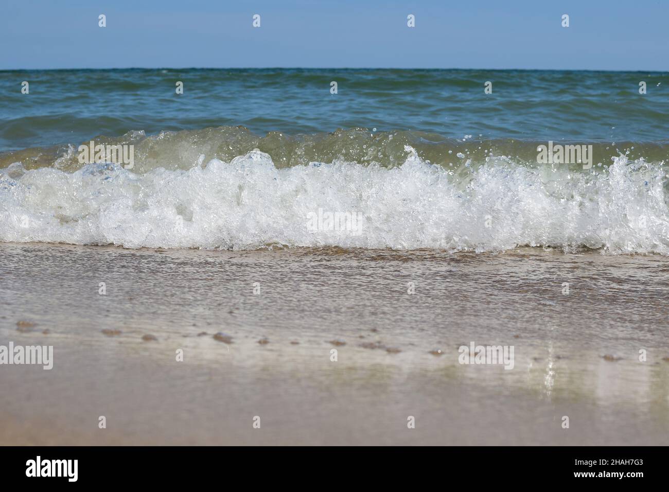 Foamy sea waves roll on the sandy daytime beach Stock Photo Alamy