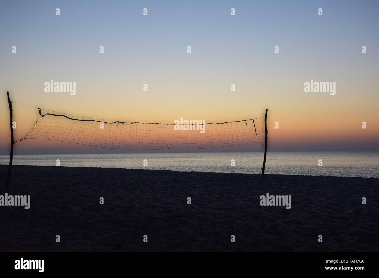 On an evening empty sandy beach, a homemade volleyball net with a
