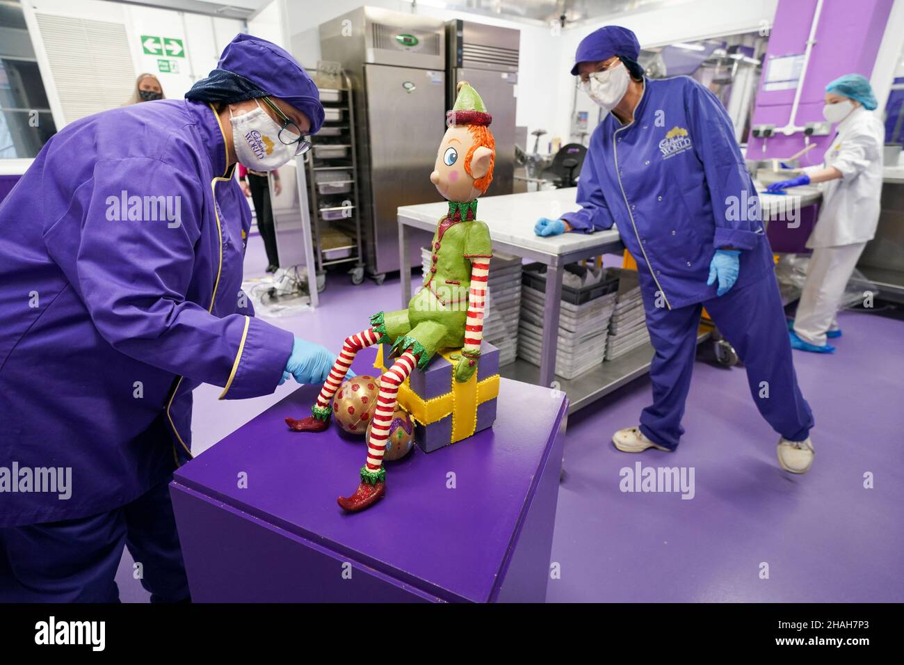 Chocolatiers Dawn Jenks and Donna Oluban add the finishing touches to the Christmas elf creation at Cadbury World in Bournville. The elf weighs 8kg, the equivalent of 178 standard bars of Cadbury Dairy Milk, and stands at 50cm tall. Picture date: Monday December 13, 2021. Stock Photo
