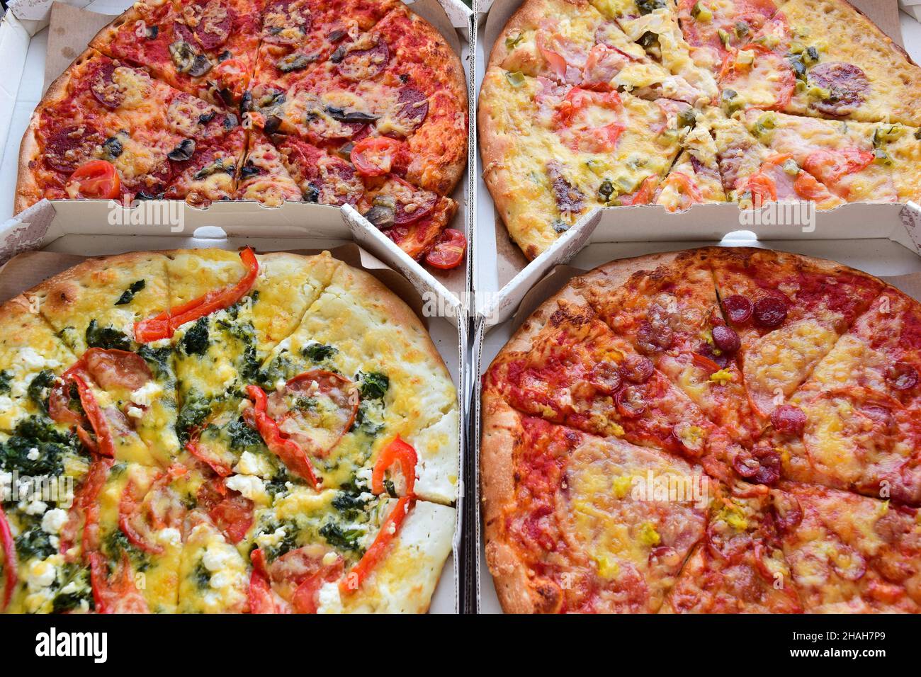 Four boxes of pizza of different types and fillings lie next to each