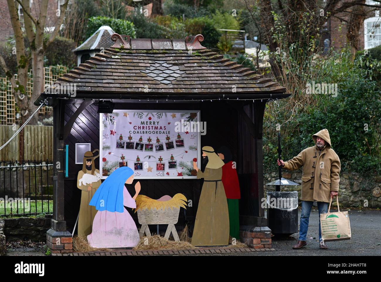 No room at the shelter! A commuter waiting at the village bus stop in Coalbrookdale, Shropshire stands outside the bus shelter as it is now locating t Stock Photo