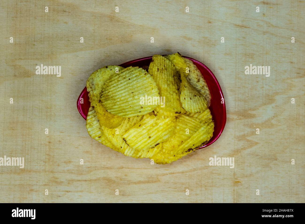 Salted Potato Wafers in Red Bowl On Wooden Table, Heap of Wafers, Copy Space, Heap of Chips, Top View Stock Photo