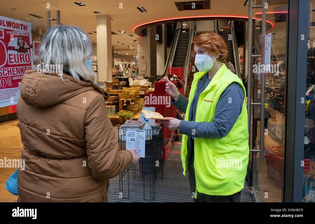 Hildesheim, Germany. 13th Dec, 2021. Kerstin Regner (r), deputy store  manager, checks vaccination certificates of customers at the entrance of a  Woolworth department store. According to the new Corona Ordinance now in