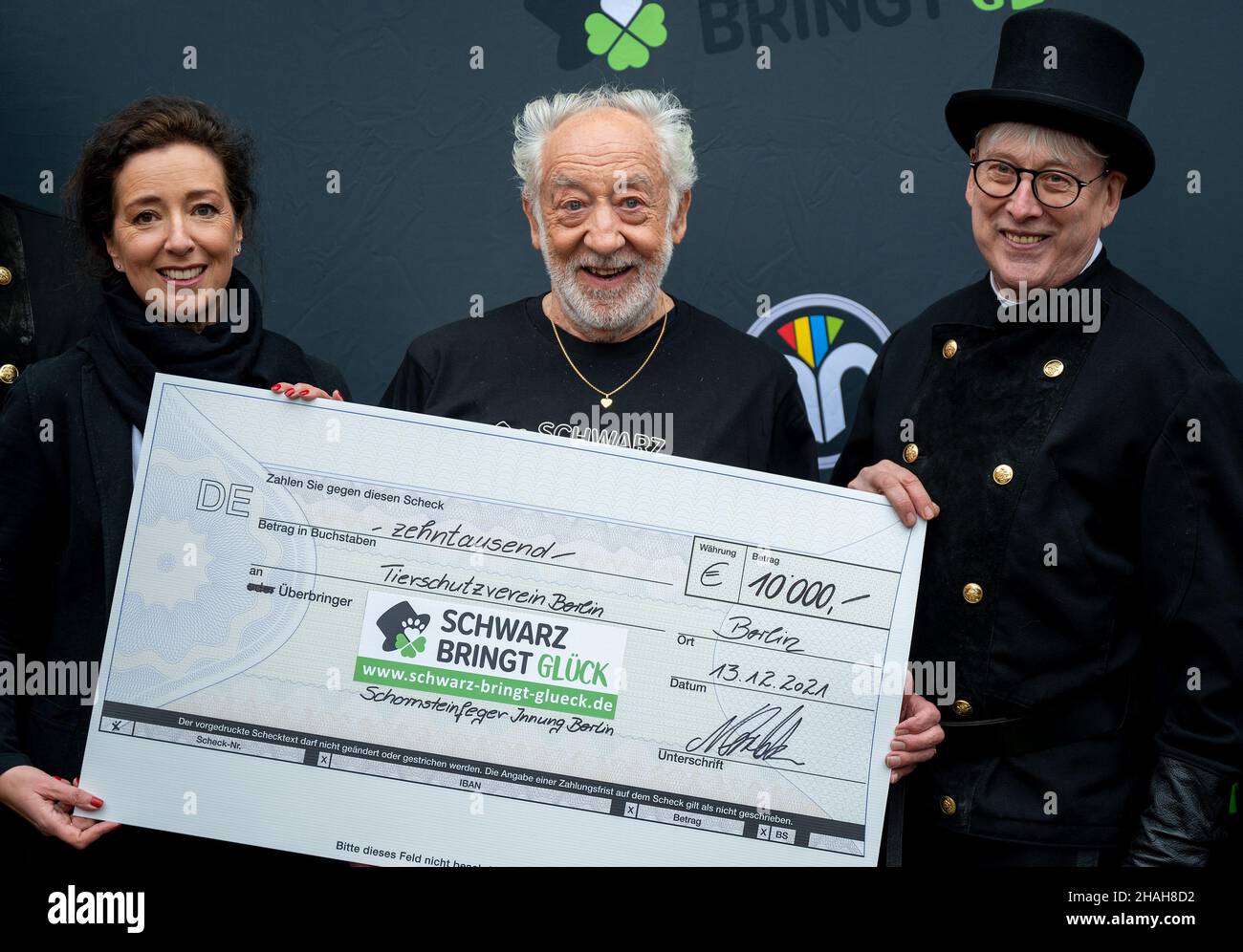 13 December 2021, Berlin: The actor Dieter Hallervorden (M), Annette Rost from the Berlin animal shelter and Norbert Skrobek, chimney sweep senior master, smile at a photo session for the handover of a 10,000 euro cheque. The money collected by the chimney sweeps will benefit the animals from the Berlin animal shelter. Photo: Monika Skolimowska/dpa-Zentralbild/dpa Stock Photo