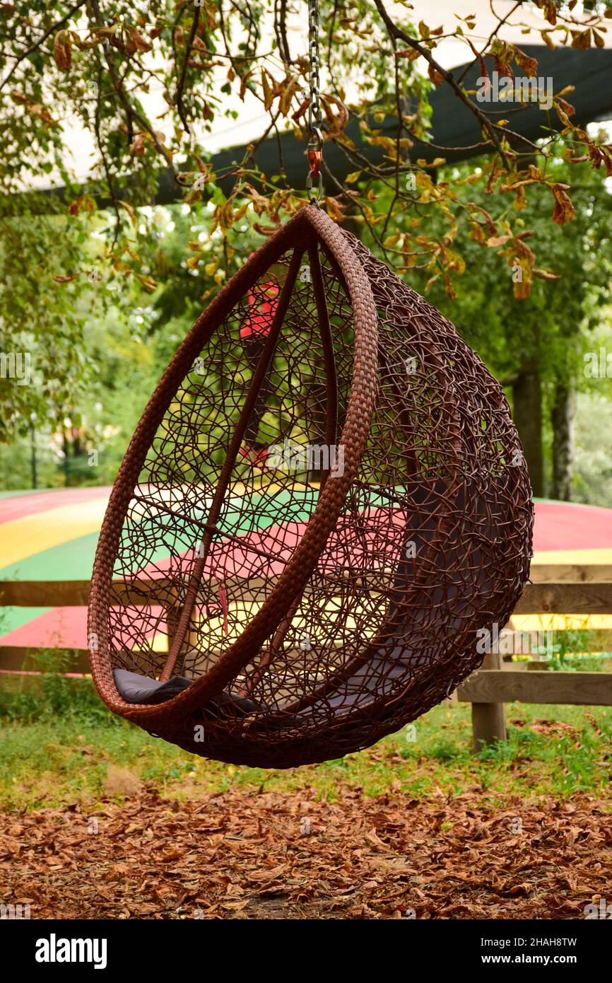 Decorative resting place in the form of a wicker swing suspended from a tree in an autumn park Stock Photo Alamy