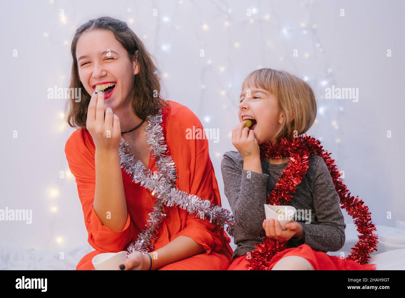 Sisters laughing and Celebrating New Year eating de twelve grapes. Spanish tradition Stock Photo