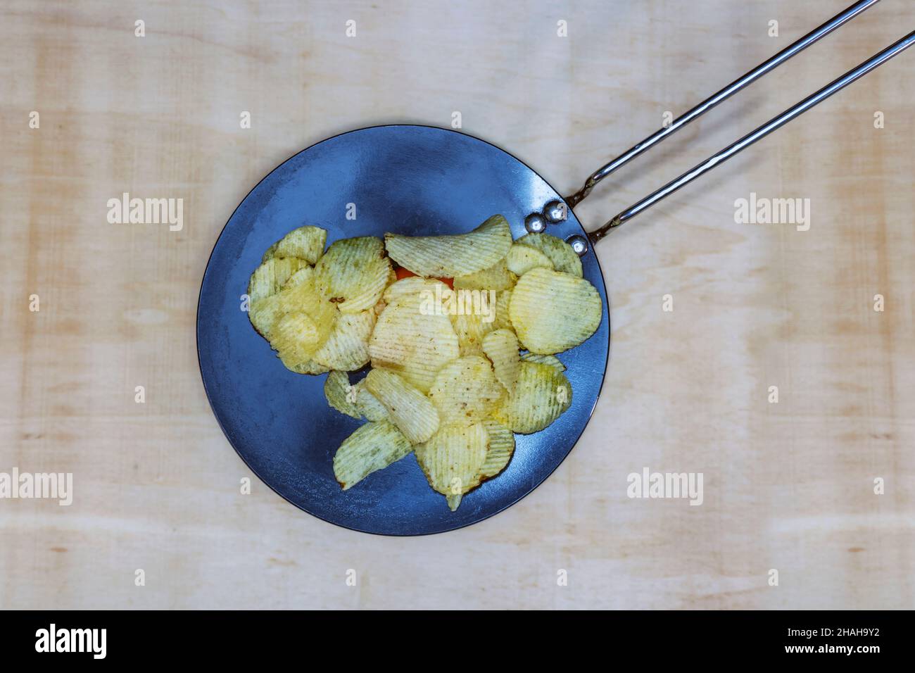 Salted Potato Wafers In Nonstick Pan On Wooden Table, Heap of Wafers