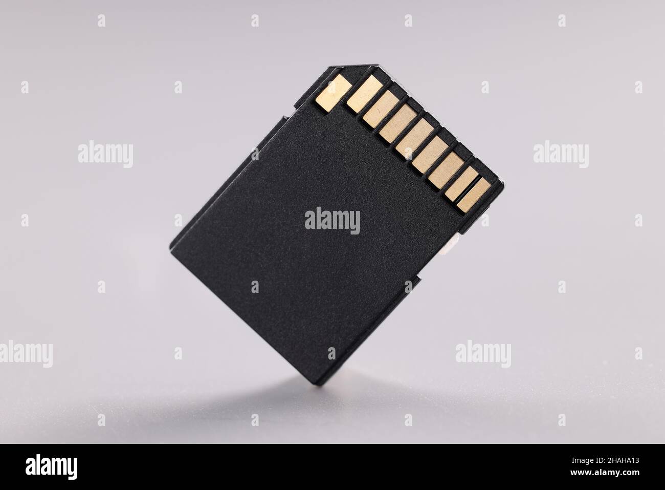 High quality black sd memory card with small gold disc on gray background Stock Photo
