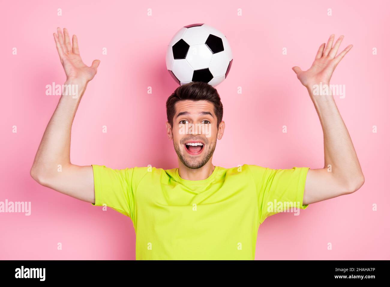 Portrait of attractive playful cheerful guy holding soccer ball on head having fun isolated over