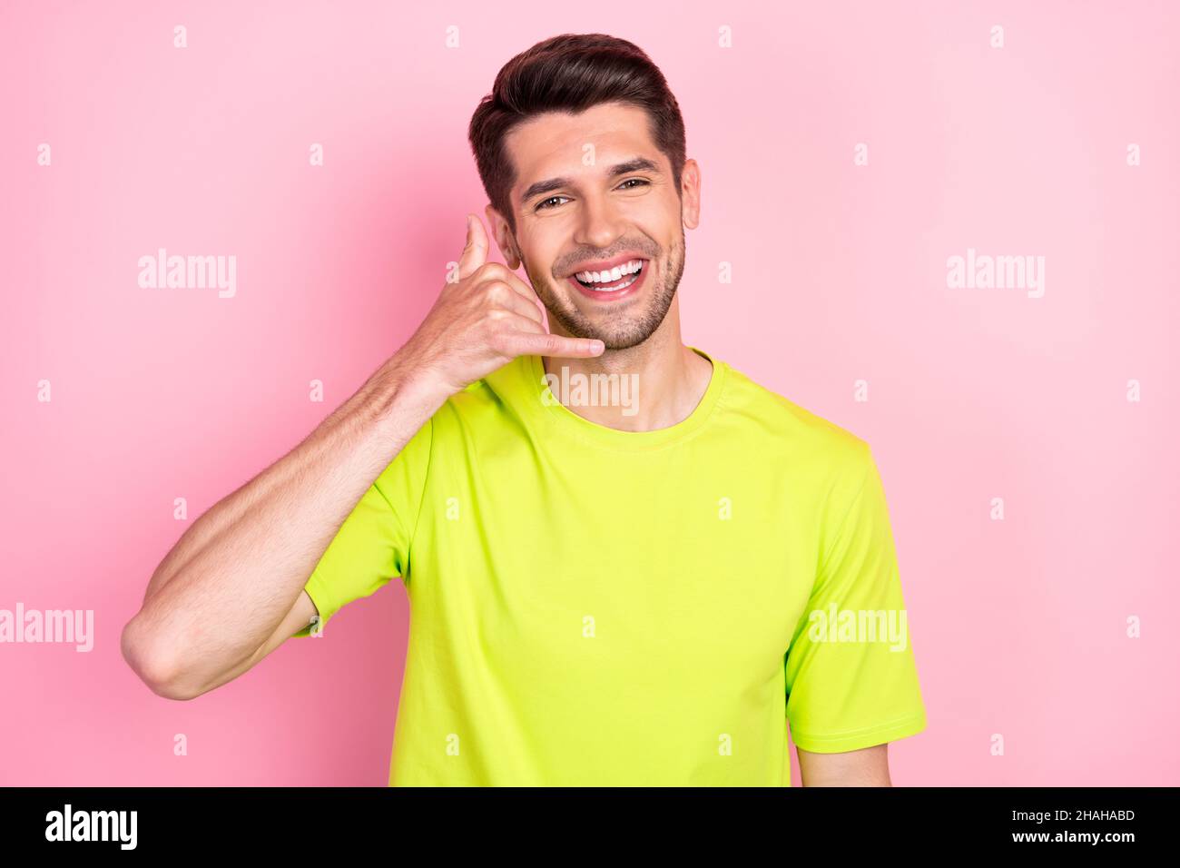 Portrait of attractive cheerful guy showing call me sign pretending ...