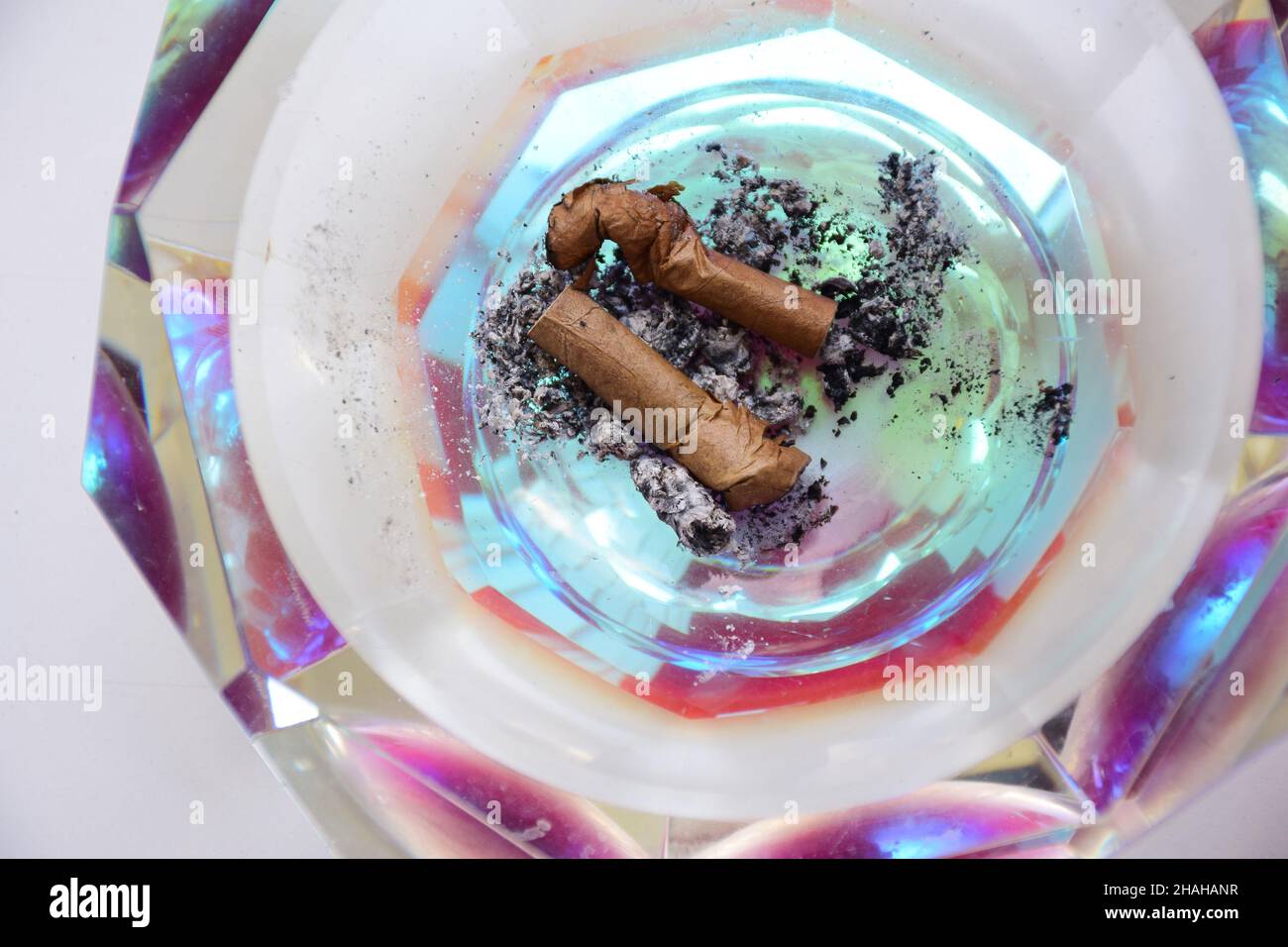 Two smoked small cigars lie on the ashes in a faceted crystal ashtray close-up Stock Photo